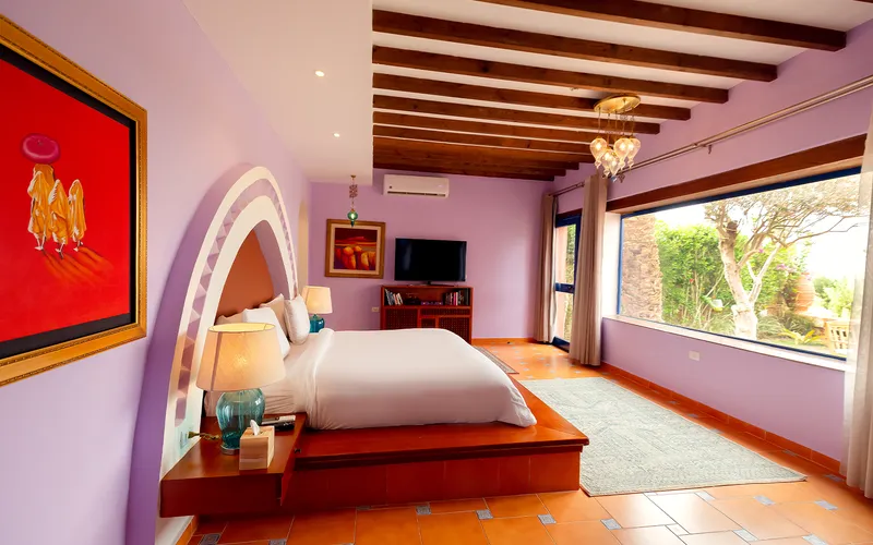 Lavender bedroom with beamed ceiling and a wide window onto the garden