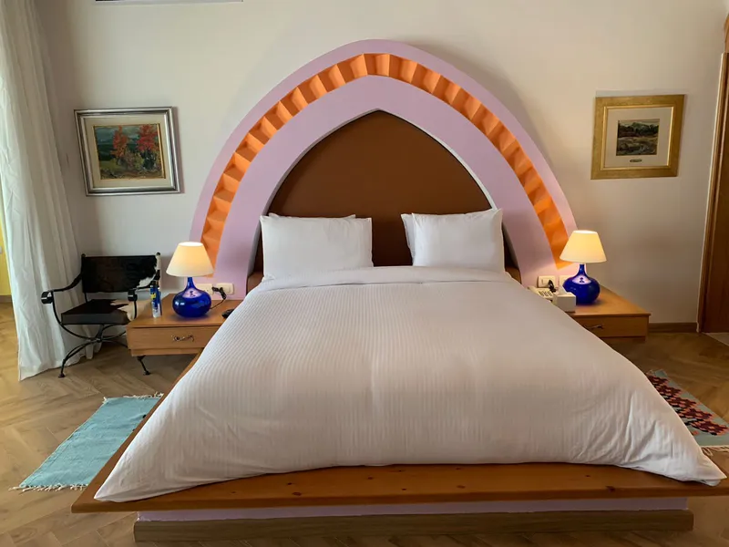 King bed under a pink and orange arched headboard