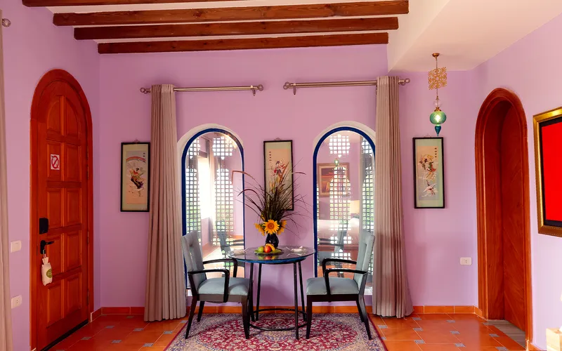 Lavender dining area with a round table between two arched windows
