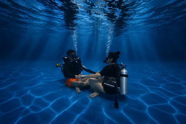 A person meditating underwater in clear blue sea